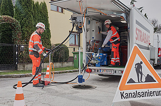 Foto von zwei Männer die eine Kanalsanierung vorbereiten