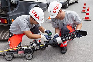 Foto von zwei Männer, welche eine Kanalinspektion mittels 3D Scanverfahren durchführen